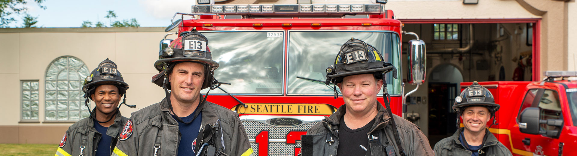 Four firefighters in front of a red fire engine