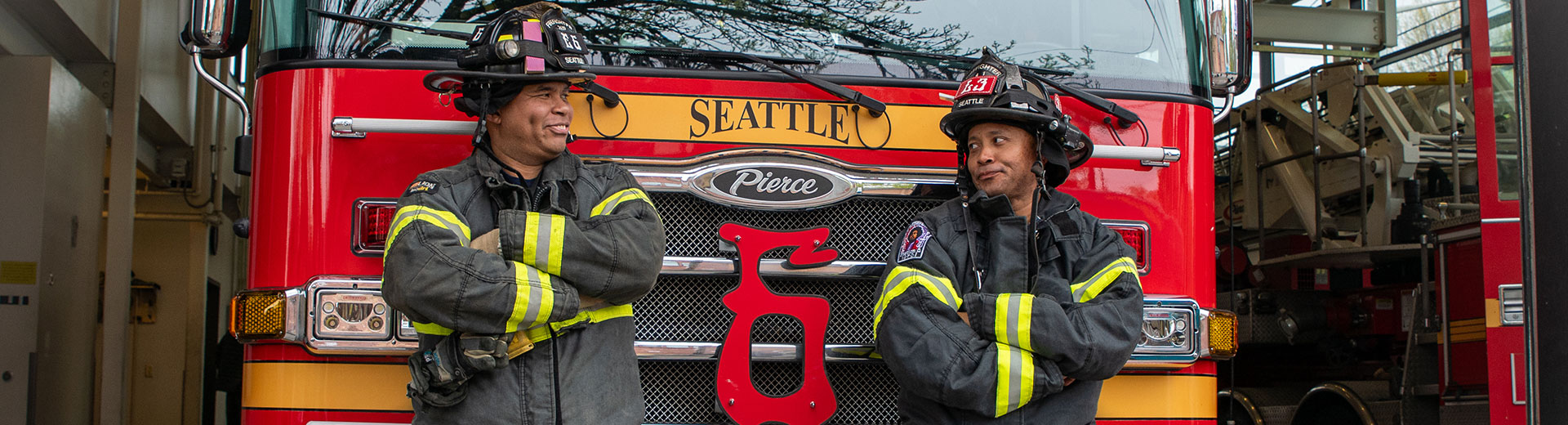 Two firefighters pose looking at each other in front of Engine 6