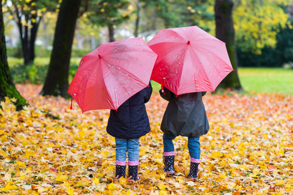 Two-children with umbrellas on a fall day